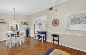 A dining area with a white table and chairs, a blue bench, a black side table, and a hanging light fixture. - 10 min walk to DT! Fire Pit-Pet Friendly! A true DT retreat! (Mount Dora)