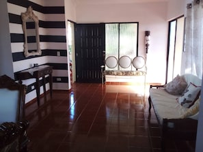 A room with a striped wall, a large mirror, a bench with round mirrors, a sofa with cushions, and a door with a view. - The Beauty of Samana (Samaná)