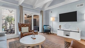 Een moderne woonkamer met een bank, een ronde salontafel, een televisie en een dressoir.