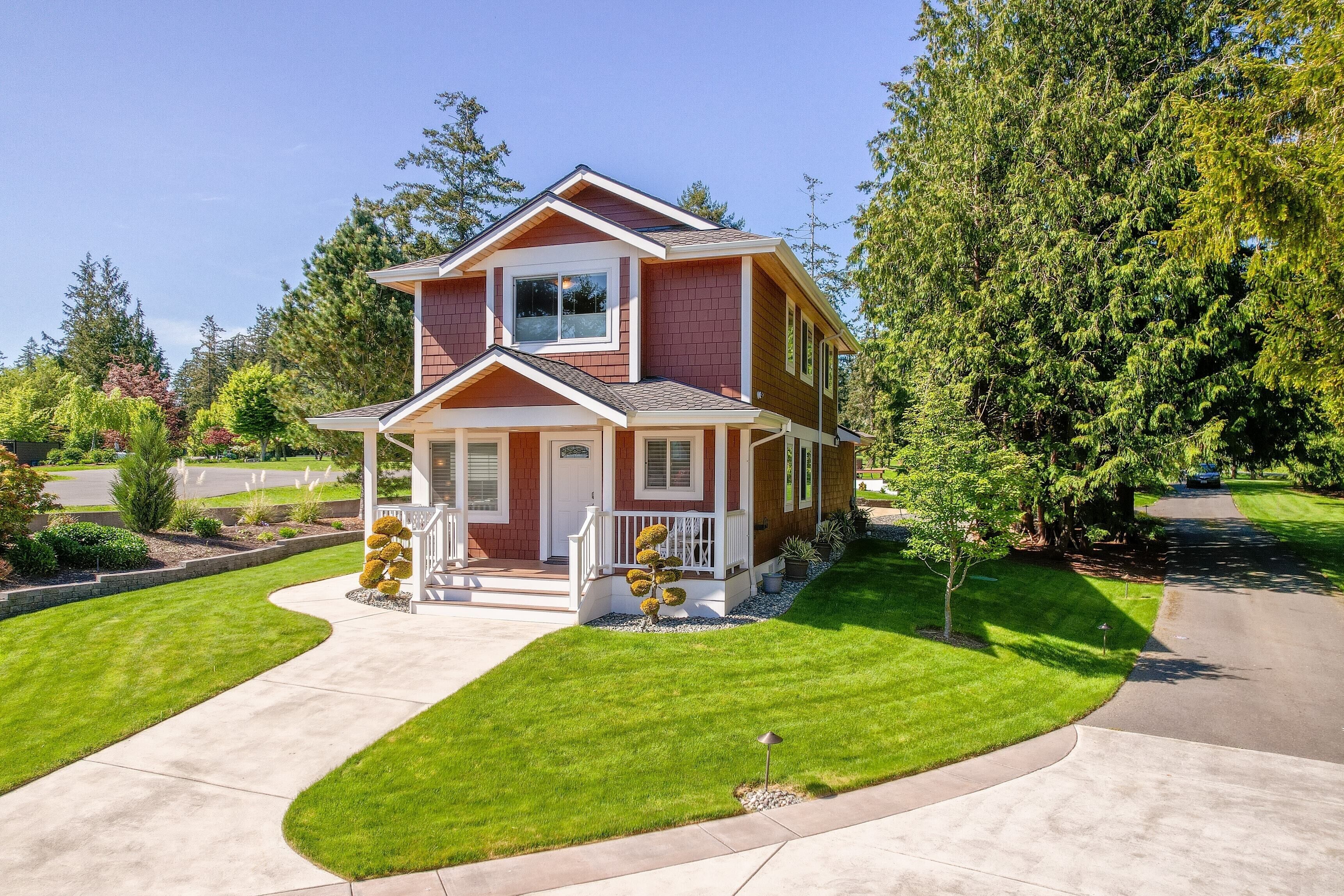 A two-story house with a front porch, a well-maintained lawn, and a driveway.