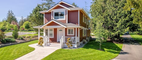 A two-story house with a front porch, a well-maintained lawn, and a driveway.