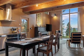 A modern kitchen with a dining area, large windows, and a view of the outdoors. - Crows Nest by Avantstay Accessible Home w/ Views (Clinton)