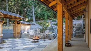 A covered patio with a fire pit, outdoor seating, and a staircase leading to a stone deck. - Crows Nest by Avantstay Accessible Home w/ Views (Clinton)