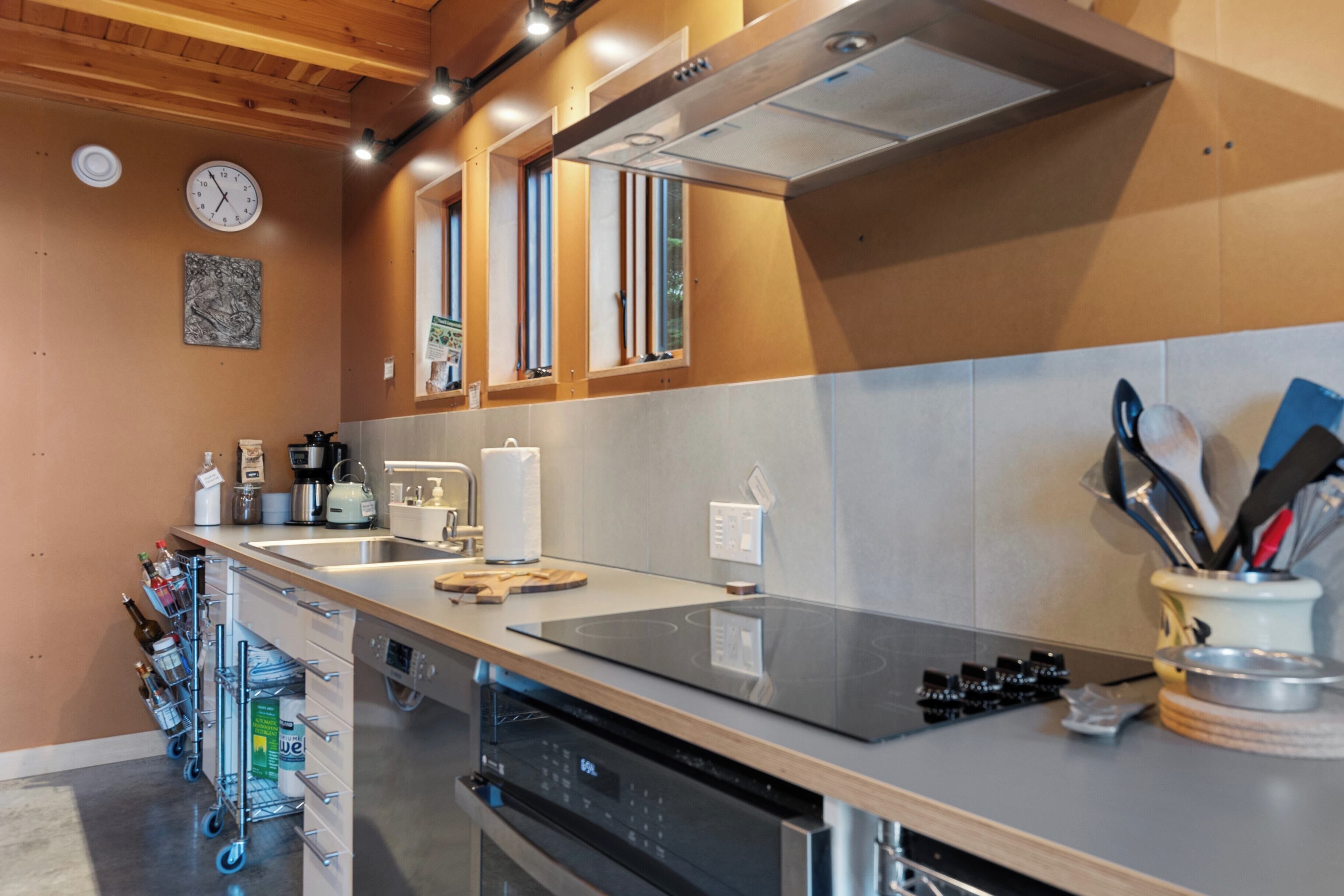 Una cocina moderna con electrodomésticos de acero inoxidable, horno empotrado y una encimera amplia.