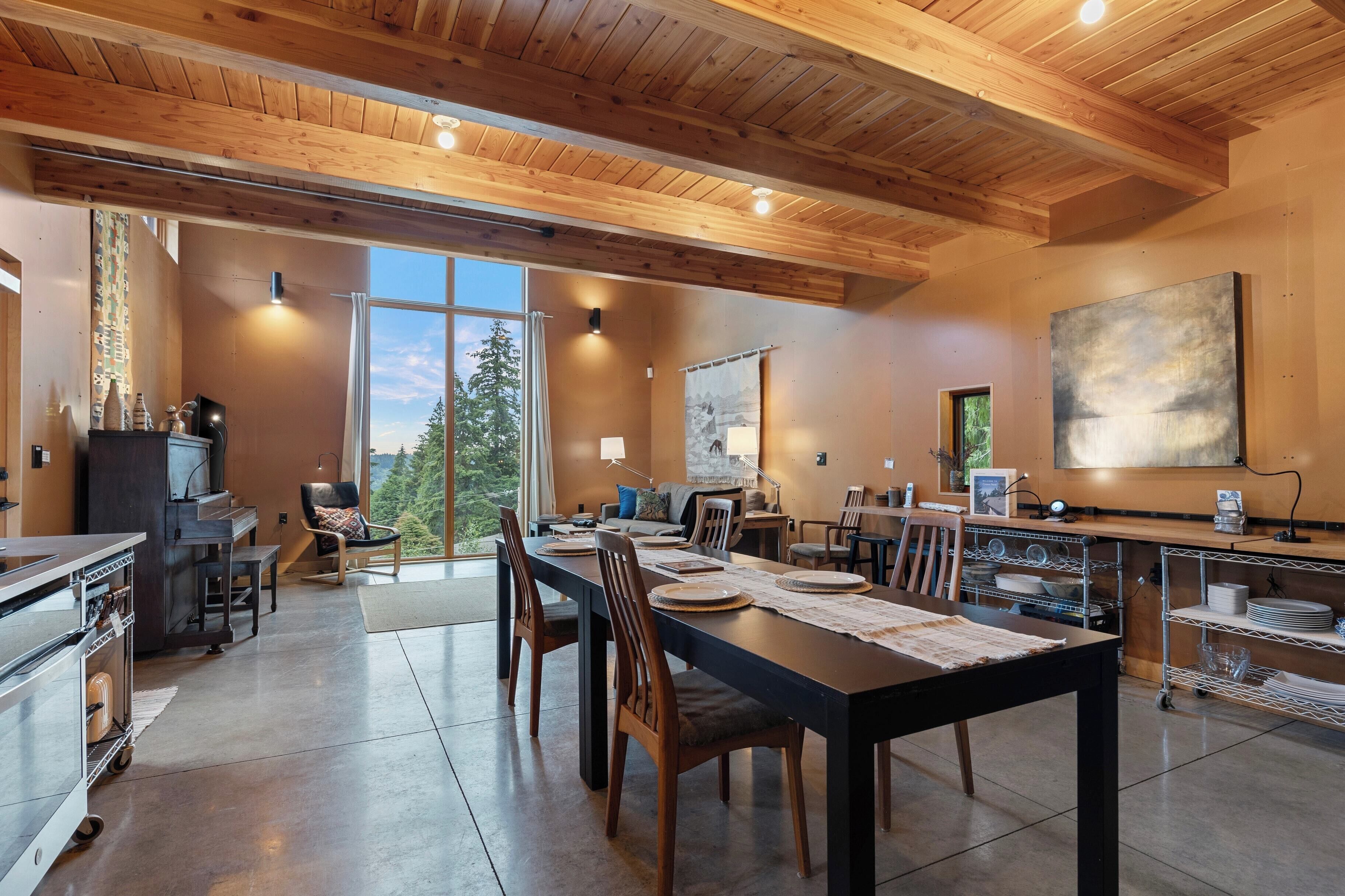 A spacious dining area with a long table, wooden chairs, and a kitchen area with a grill and counter space.
