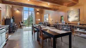 A spacious dining area with a long table, wooden chairs, and a kitchen area with a grill and counter space. - Crows Nest by Avantstay Accessible Home w/ Views (Clinton)