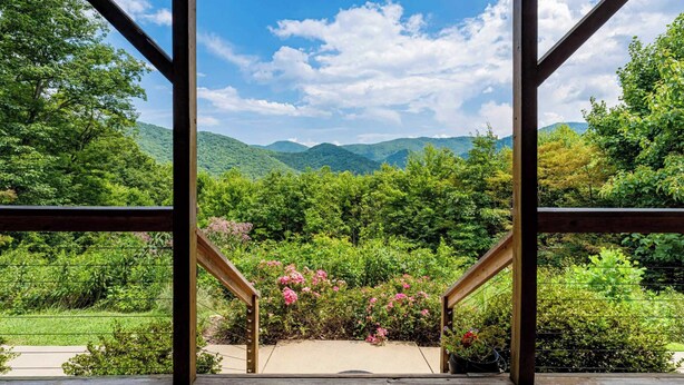 A wooden staircase leading to a balcony with a view of lush greenery and distant mountains. - Among the Clouds by Avantstay Views + Hot Tub (Candler)