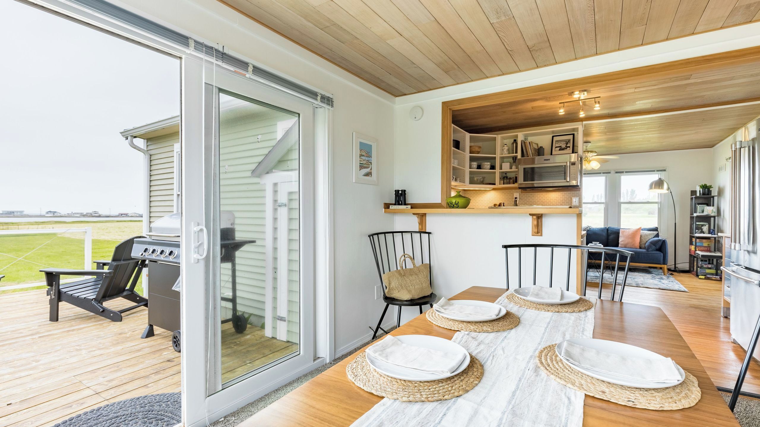 Eine moderne Küche mit eingebautem Backofen und Mikrowelle, ein Essbereich mit Tisch für vier Personen und eine Glastür, die auf eine Terrasse führt.