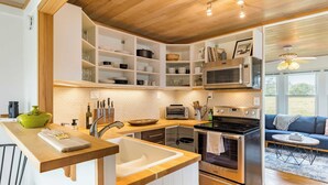 A modern kitchen with built-in cabinets, a microwave, a toaster, and an oven. - Swan Lake Cottage by Avantstay Views + Firepit (Oak Harbor)