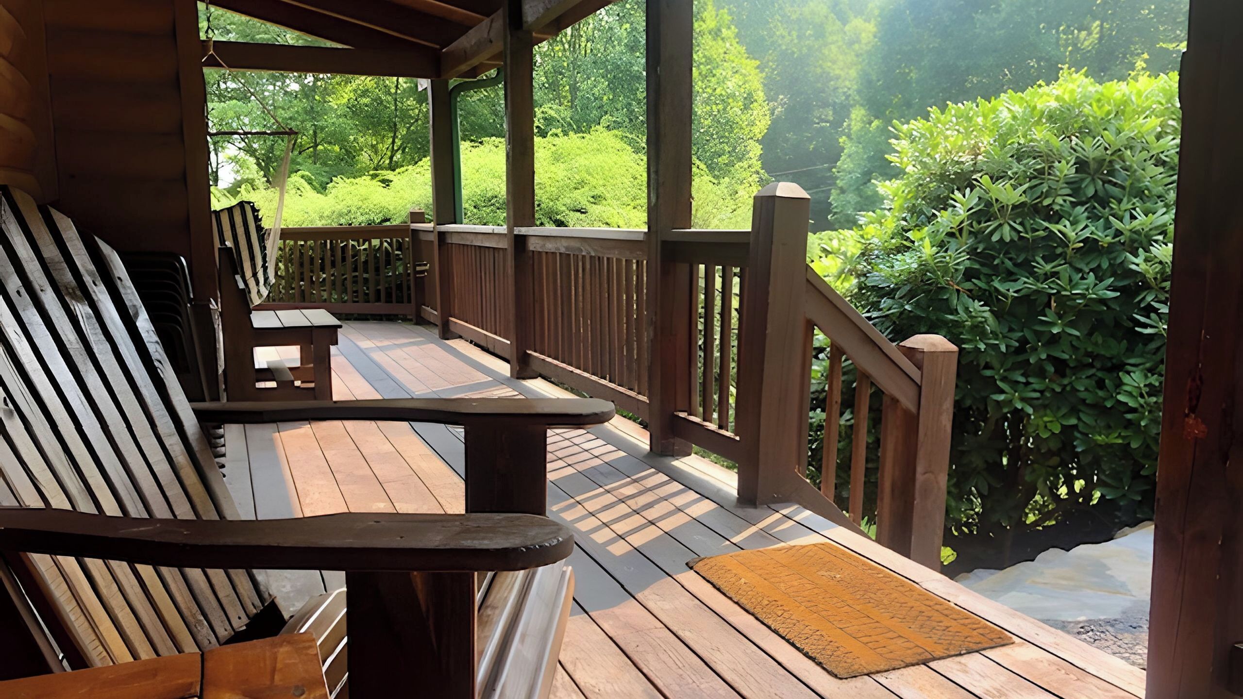A wooden deck with a bench and a table, surrounded by a wooden railing, overlooking a lush green landscape.