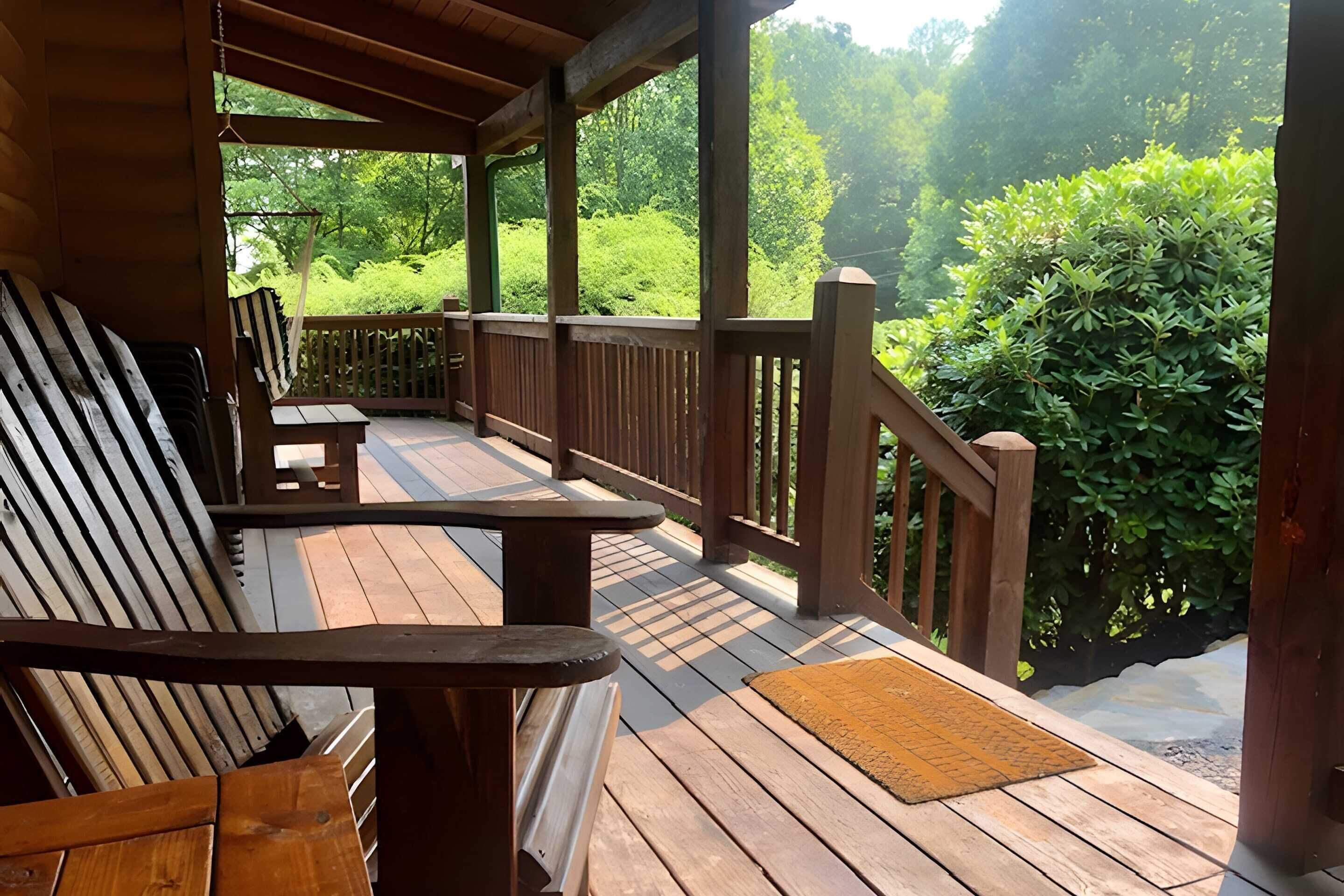 A wooden deck with a bench and a small table, surrounded by lush greenery.