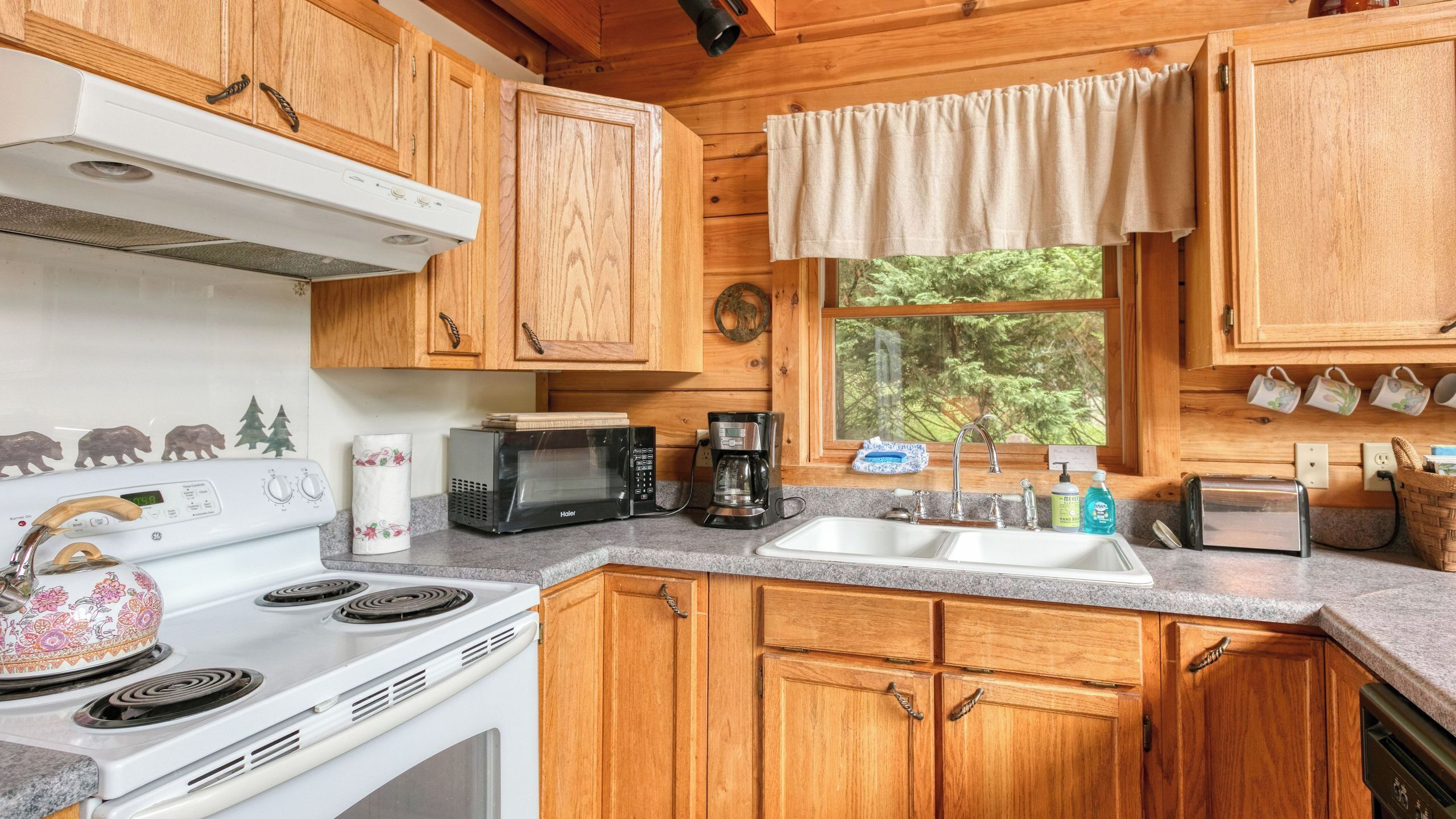 A kitchen with wooden cabinets, a stove, a microwave, a coffee maker, and a sink.