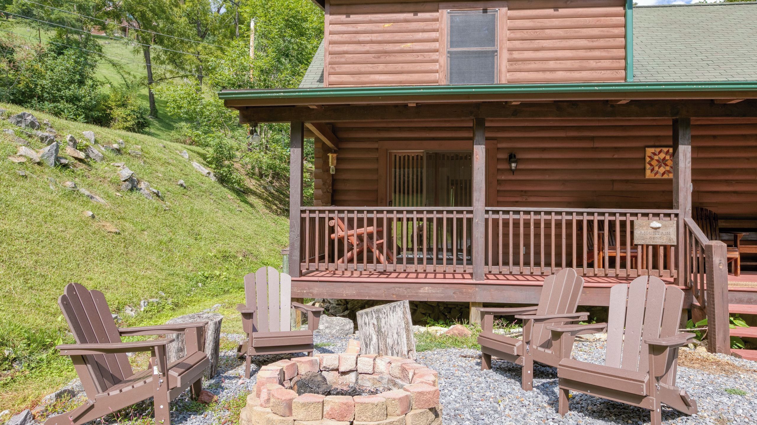 A wooden cabin with a porch, outdoor seating, and a fire pit.