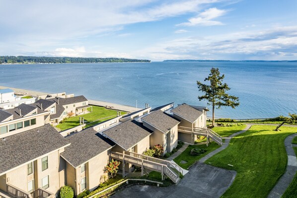 A residential area with modern houses, a clear view of the water, and a well-maintained lawn.