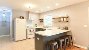 A modern kitchen with a central island, built-in appliances, and bar stools. - Best of the Blue Ridge by Avantstay A+ Location (Arden)