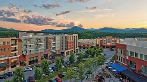 A downtown area with multi-story buildings, a parking lot, and a view of distant mountains. - Best of the Blue Ridge by Avantstay A+ Location (Arden)