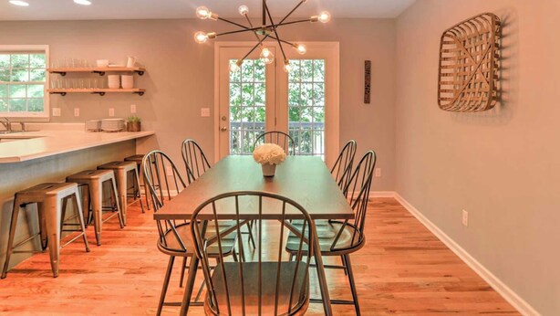 A dining area with a long table, chairs, a chandelier, and a view through a glass door. - Best of the Blue Ridge by Avantstay A+ Location (Arden)