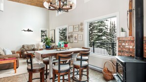 A spacious living area with a dining table, four wooden chairs, a sofa, and a fireplace. - Amazing location with private hot tub, sauna, laundry and ground level suite.  (Silver Star Mountain)