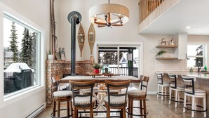 A spacious kitchen with a large island, wooden chairs, and a hanging light fixture. - Amazing location with private hot tub, sauna, laundry and ground level suite.  (Silver Star Mountain)