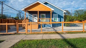 Ein zweistöckiges Haus mit einer Holzveranda und einem umzäunten Garten.