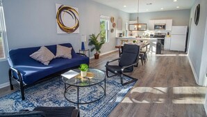 Ein modernes Wohnzimmer mit einem blauen Sofa, einem Couchtisch und einem Essbereich mit Stühlen.