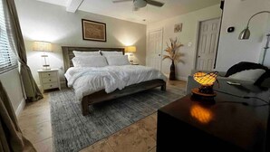 Un dormitorio con cama, mesitas de noche, lámpara, escritorio y silla.