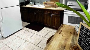 Una cocina moderna con armarios de madera, un refrigerador blanco, un microondas y una mesa de comedor de madera con un letrero de pizarra.