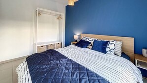 A bedroom with a bed, a nightstand, a lamp, and a hanging light fixture.