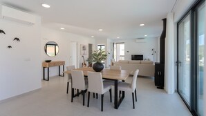 Un espacio moderno para vivir con comedor, sofá, televisor y un amplio ventanal.