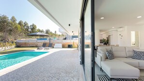Una sala de estar moderna con un sofá blanco, un tapete con estampado blanco y negro y vistas a una zona de piscina al aire libre.