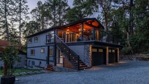 Ein zweistöckiges Haus mit einer Veranda, einer Treppe und einer Garage.