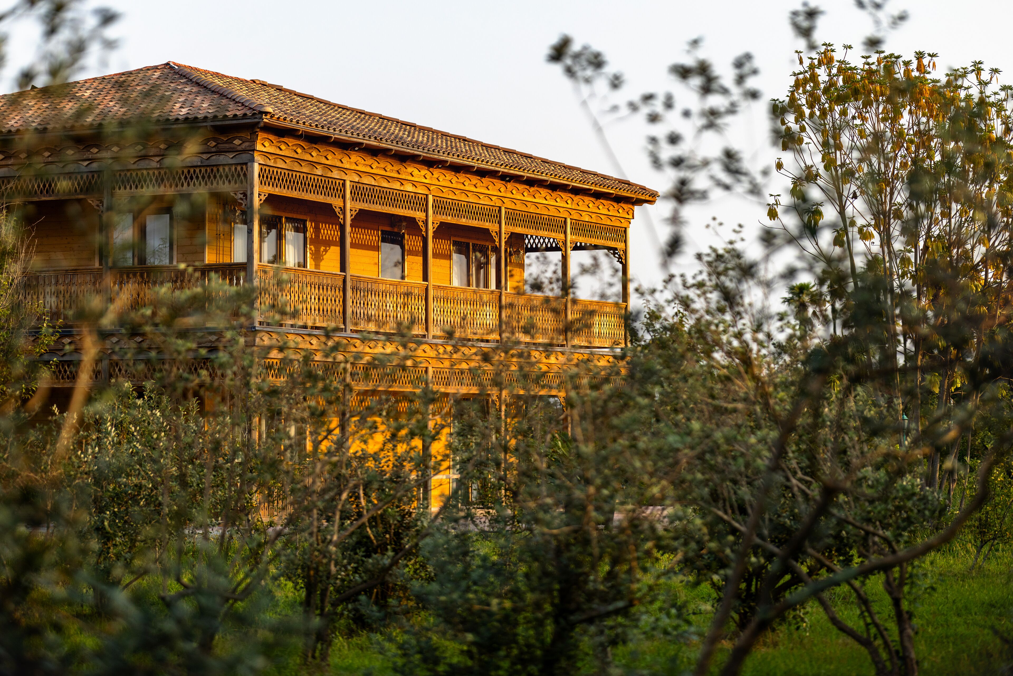 Une maison en bois dotée d’un balcon, entourée de verdure.