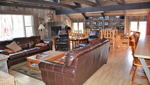 A rustic living room with leather furniture, a fireplace, and a wall adorned with framed pictures. - Hanging Bull Lodge (Encampment)