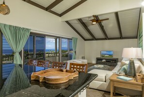 A spacious living area with a large window overlooking the ocean, a ceiling fan, and a cozy seating arrangement. - Stunning Ocean Views! Renovated Wailea Ekolu 502 (Wailea)