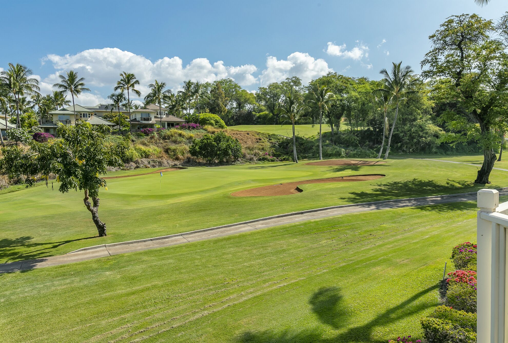 A golf course with well-maintained grass, sand bunkers, and a clear sky.