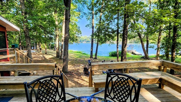 A wooden deck with benches overlooking a lake, surrounded by trees. - Roddy's Roost Lakefront Cabin - Hot Springs AR
 (Hot Springs)