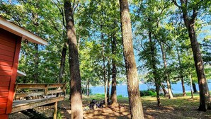 A cabin with a deck overlooking a lake, surrounded by tall trees. - Roddy's Roost Lakefront Cabin - Hot Springs AR
 (Hot Springs)