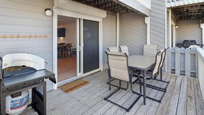 A covered patio with a grill, table, chairs, and a sliding door leading to an indoor area.