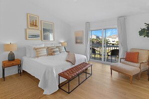 Une chambre à coucher avec un lit, un banc, une chaise et une vue sur l’extérieur.
