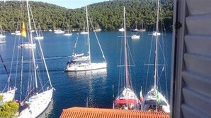 A marina with multiple sailboats docked in calm waters, surrounded by lush greenery. - Sponga 2 Apartment with balcony and sea view (Polače)