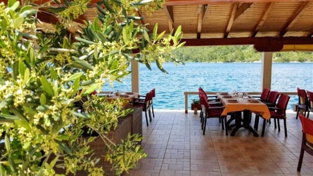 An outdoor dining area with tables and chairs, overlooking a body of water. - Sponga 2 Apartment with balcony and sea view (Polače)