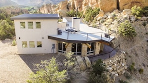 Une maison moderne à deux étages, dotée d’un toit plat, de grandes fenêtres et de fondations en pierre.