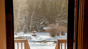 A wooden deck with a view of a snowy landscape, including a pond and trees. - Located on the river, facing the Mountains (Red River)