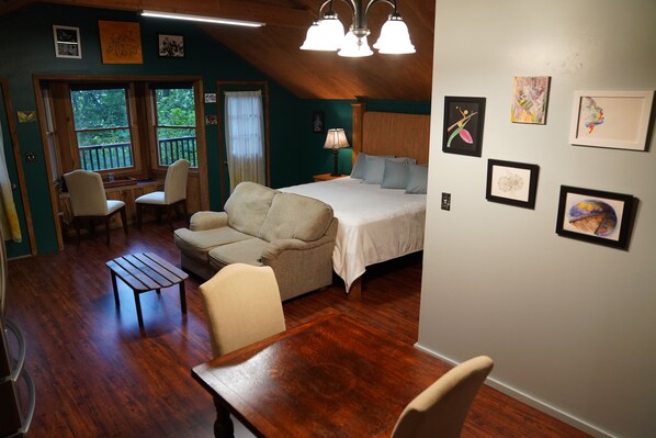 Relax in a spacious room with a high ceiling, featuring a comfortable bed, sofa, and artwork-adorned walls.