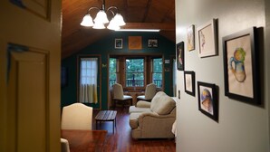A cozy living room with a wooden ceiling, a sofa, a table, and chairs. There are framed pictures on the wall. - Peaceful Smoky Mountain Cabin Near Cades Cove (Townsend)