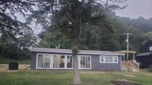 Een gelijkvloers huis met een grote schuifdeur, een klein terras en een gazon.