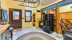 A kitchen with a wooden interior, a black refrigerator, and a hanging light fixture. - Unique Finger Lakes Converted Horse Barn w/ Patio! (Geneva)