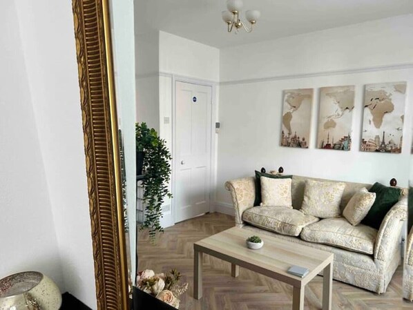 Un salon avec un canapé, une table basse et un grand miroir.