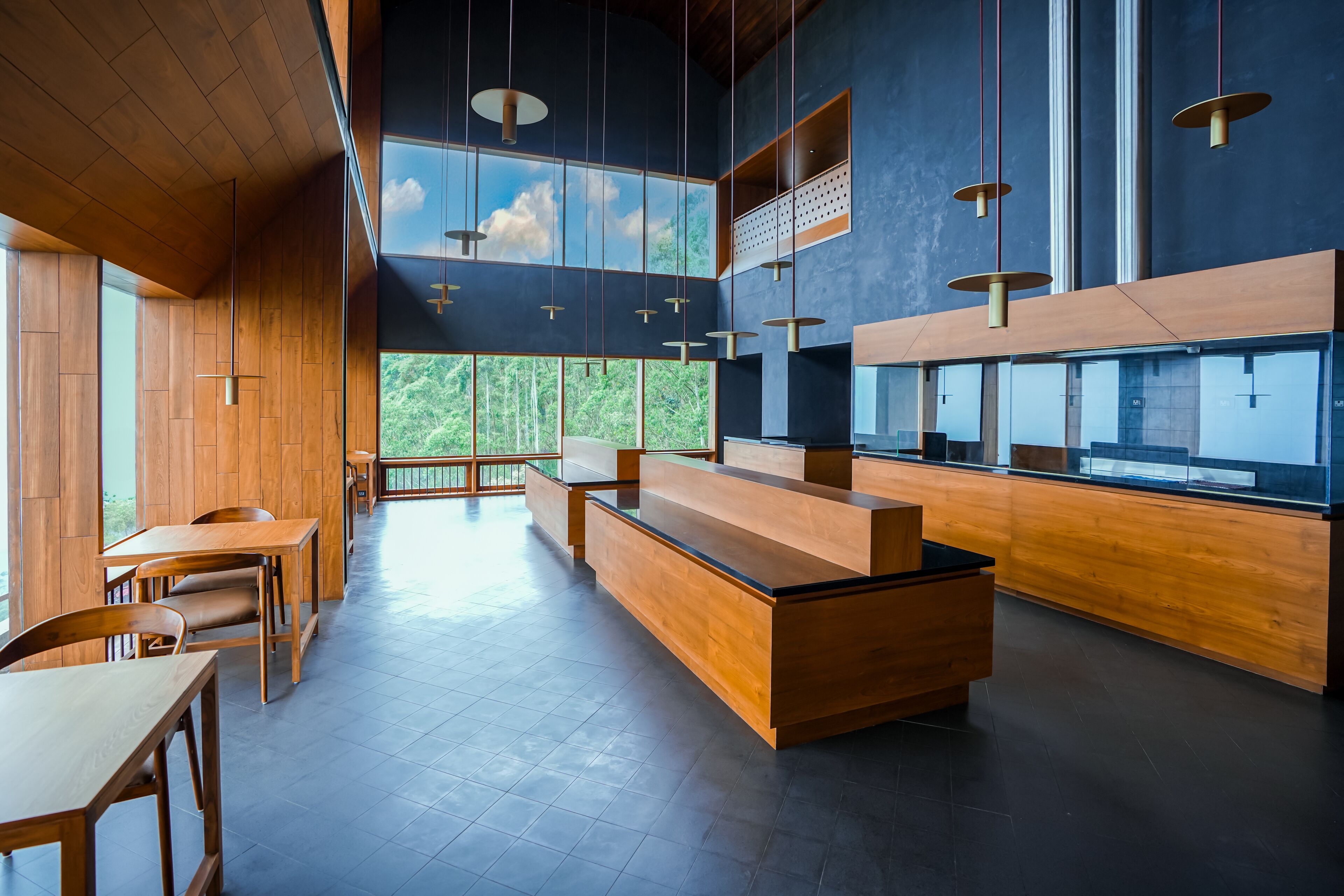 Een modern interieur met houten meubels, een receptiebalie en grote ramen met uitzicht op groen.