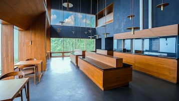 Een modern interieur met houten meubels, een receptiebalie en grote ramen met uitzicht op groen.